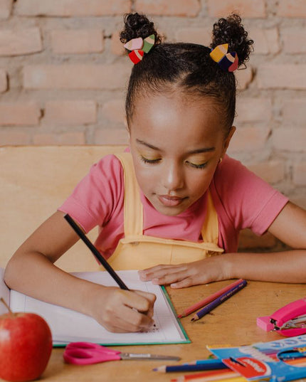 Girl wearing pencil hair ties writing in a notebook