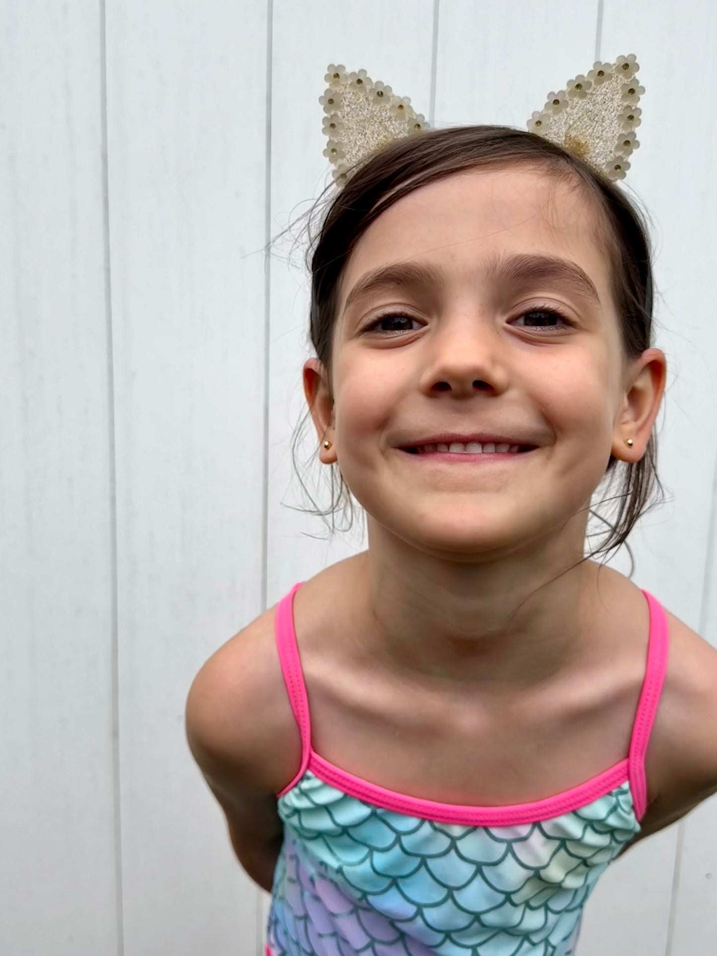Girl smiling wearing gold daisy cat ears headband