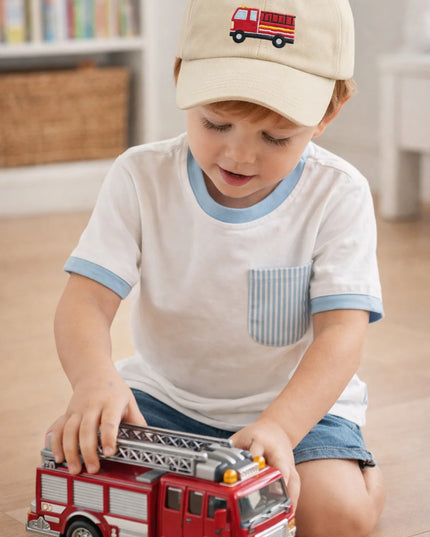 Boy playing with a firetruck toy wearing a firetruck baseball hat