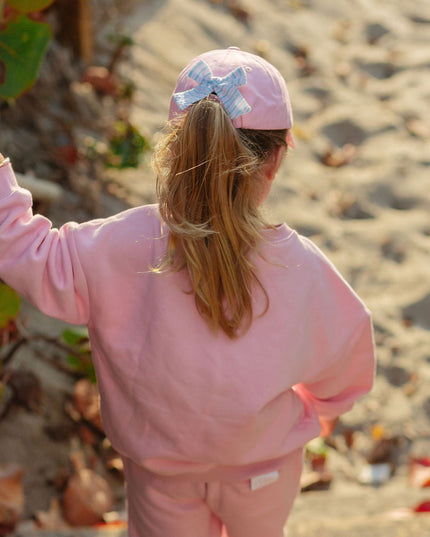 Girl wearing pink baseball hat with blue and white bow