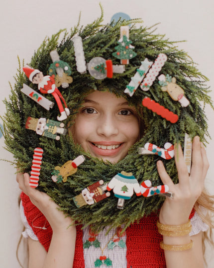 Girl holding a wreath decorated with various holiday hair clips