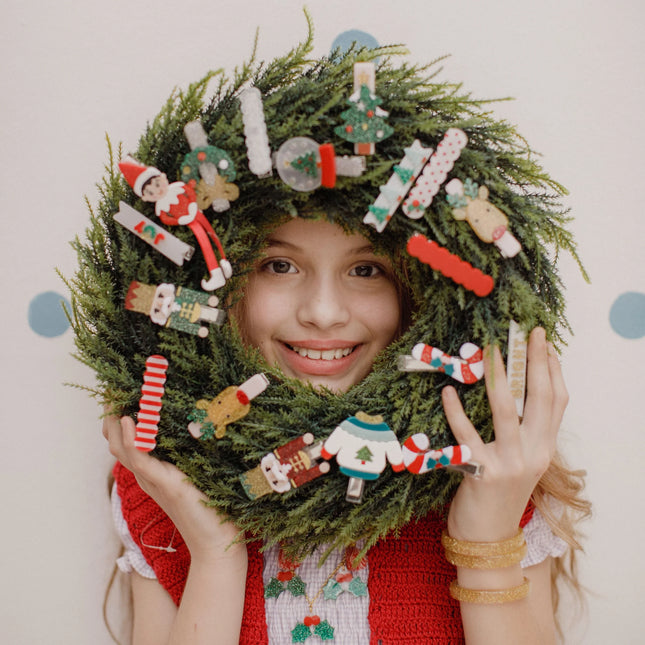 Girl holding a wreath decorated with various holiday hair clips