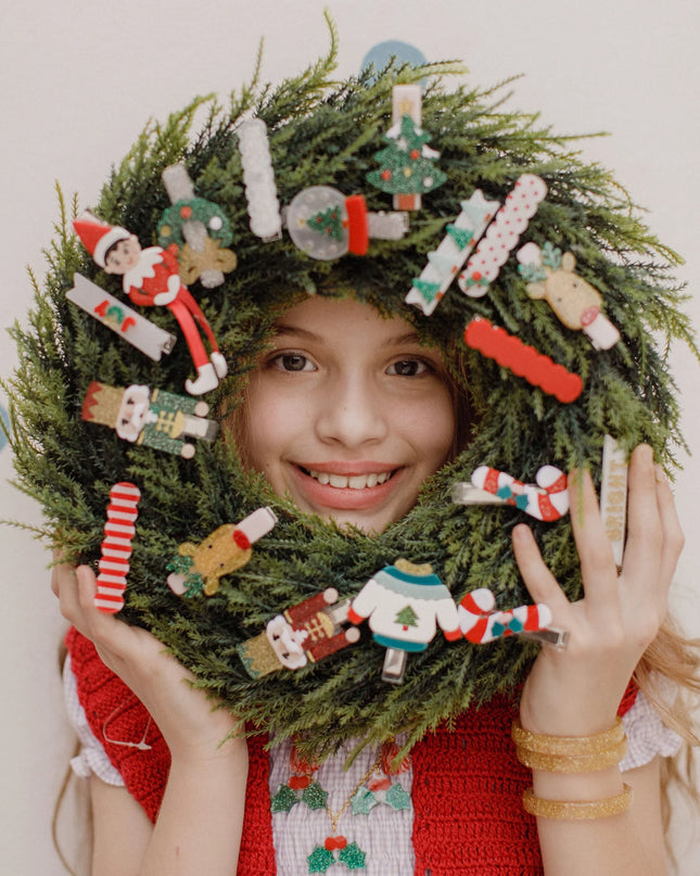 Girl holding a wreath decorated with various holiday hair clips