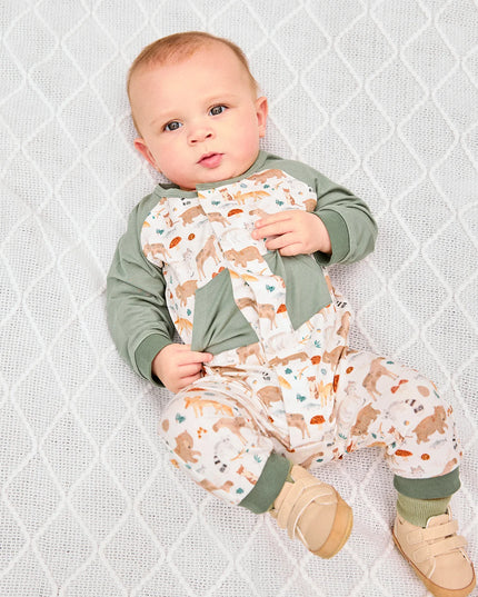 Baby wearing romper with green raglan sleeves, pockets, and cuffs, featuring an all-over woodland animal print.