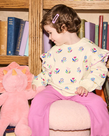 Child Wearing  outfit with floral sweatshirt and purple pants 