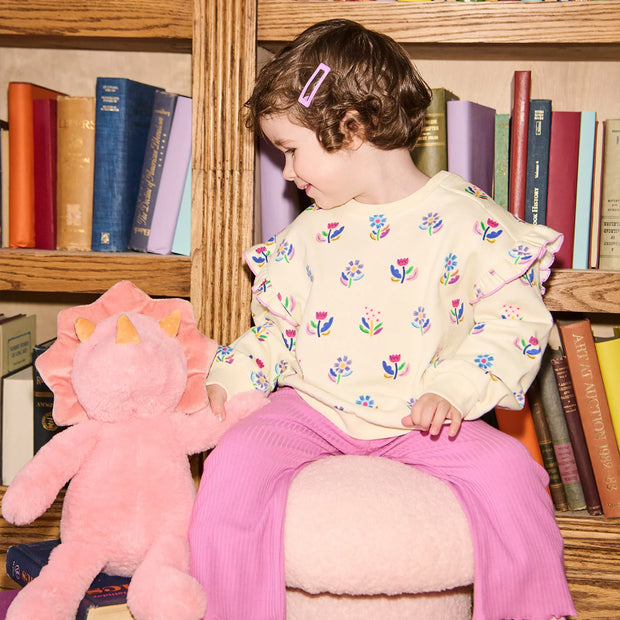 Child Wearing  outfit with floral sweatshirt and purple pants 