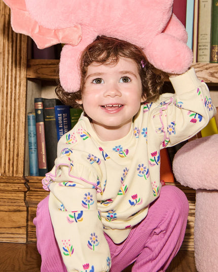 Child Wearing  outfit with floral sweatshirt and purple pants 