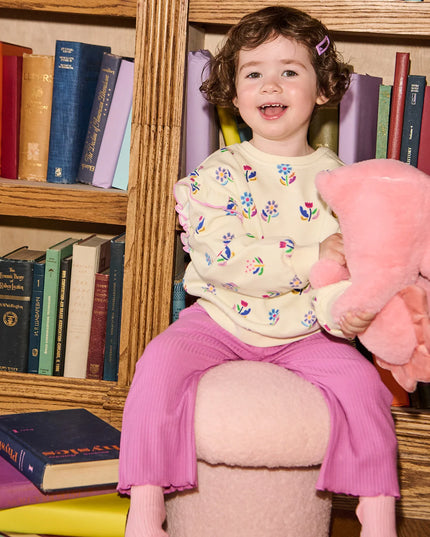 Child Wearing  outfit with floral sweatshirt and purple pants 