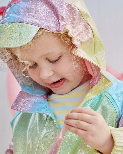 Girl wearing rainbow unicorn sparkle raincoat with magnetic closures