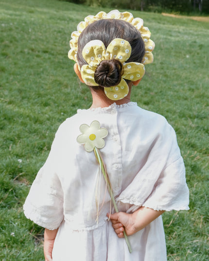 Girls holding daisy wand with streamers behind her back