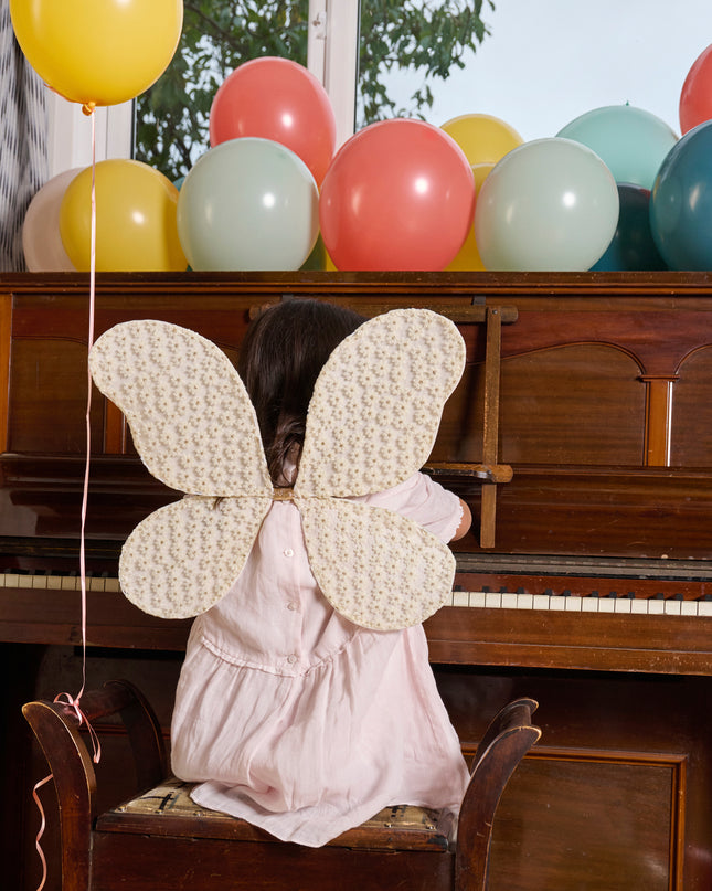 Girl Wearing Crochet Daisy Fair Wings Sitting at Piano