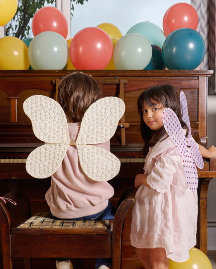 Girls sitting at piano wearing fairy wings