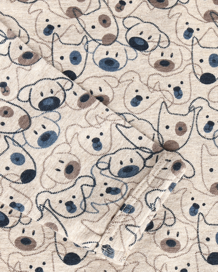 Close-up of a cream-colored fabric with an all-over cartoon dog face pattern in navy blue, dark brown, and light beige.