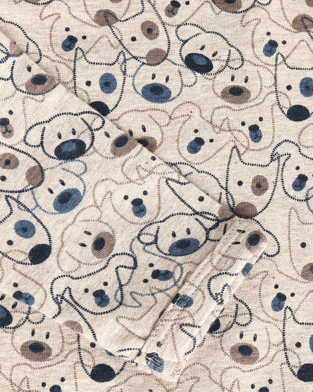 Close-up of a cream-colored fabric with an all-over cartoon dog face pattern in navy blue, dark brown, and light beige.