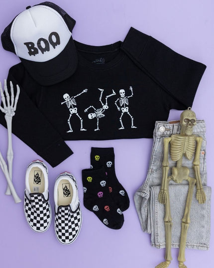 Flat-lay of Black Sweatshirt with dancing skeletons, "boo" hat and checkered sneakers