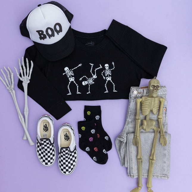 Flat-lay of Black Sweatshirt with dancing skeletons, "boo" hat and checkered sneakers