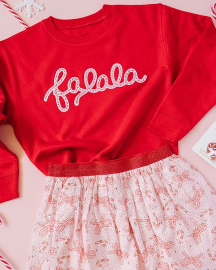 Flat-lay of red fa-la-la sweatshirt and pink tutu with candy cane and bow print 