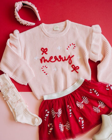 Flatlay featuring red tutu with red and white sequin candy canes and bows, pink merry sweater, headband and tights