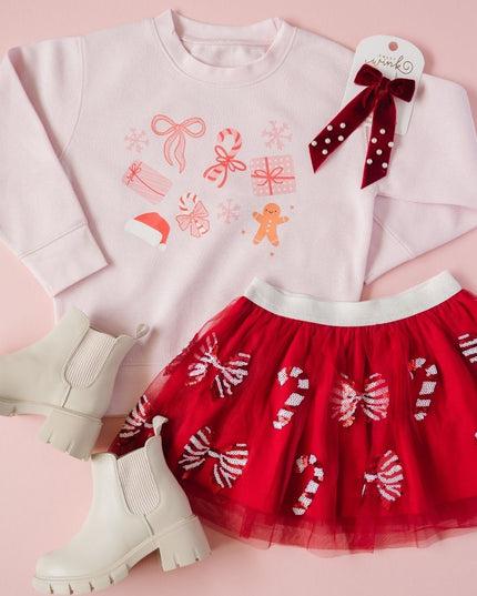 Flatlay showing ink crewneck sweatshirt with fun Christmas graphics, red tutu with candy cane and bows and accessories