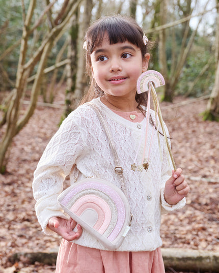 Girl wearing a glitter rainbow purse and holding a glitter rainbow wand