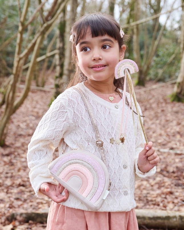 Girl wearing a glitter rainbow purse and holding a glitter rainbow wand