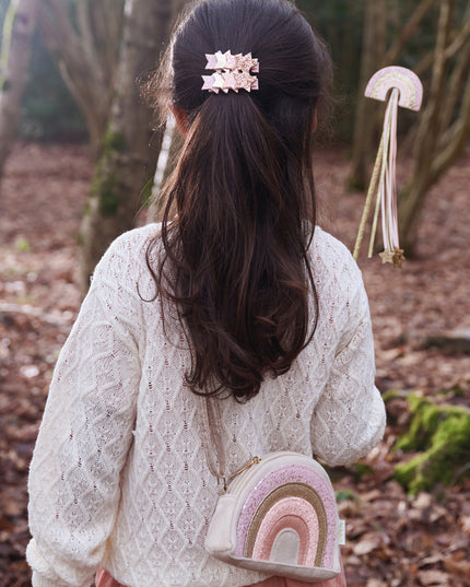 Girl wearing a glitter rainbow purse and holding a glitter rainbow wand