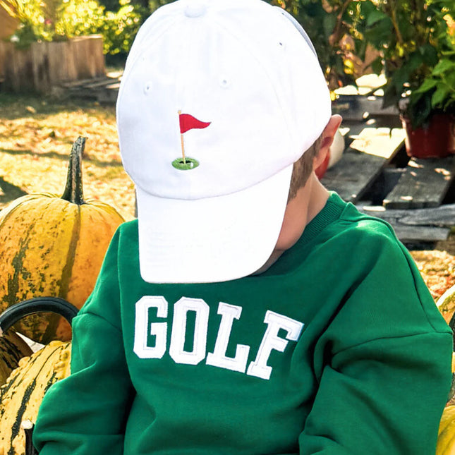 boy wearing green sweatshirt with white golf appliqué and golf flag hat