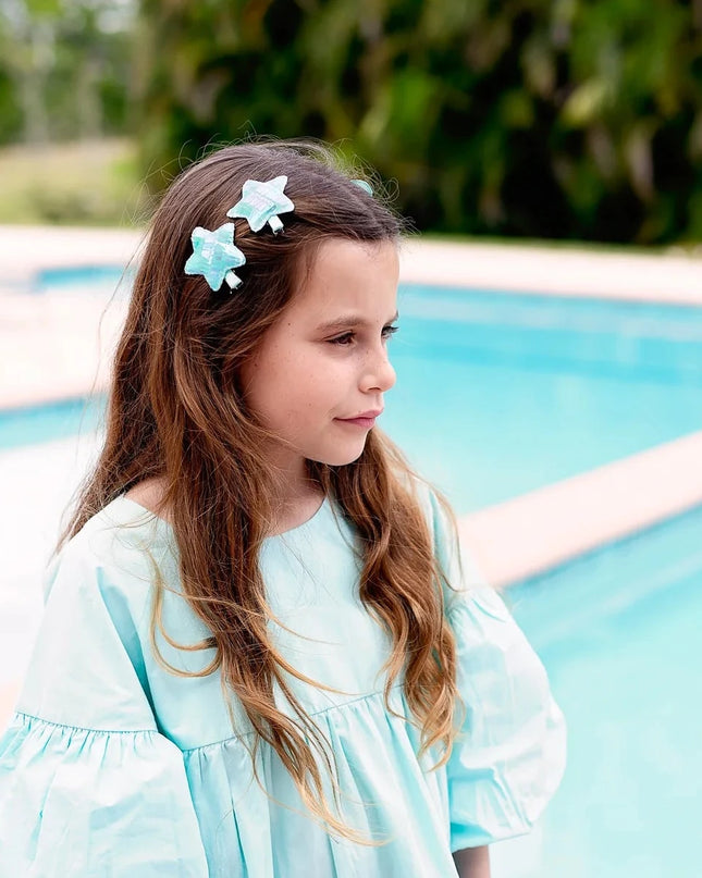 Girl standing by pool wearing turquoise star hair clips
