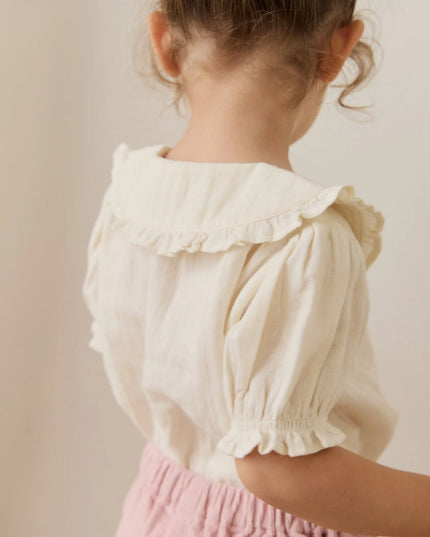 Girls wearing white button down blouse with ruffled collar and sleeves