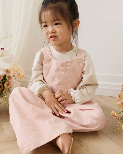 Girl wearing pink overalls with white flowers