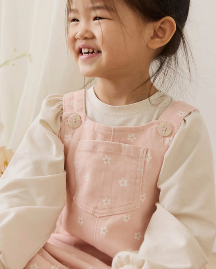 Girl wearing pink overalls with white flowers