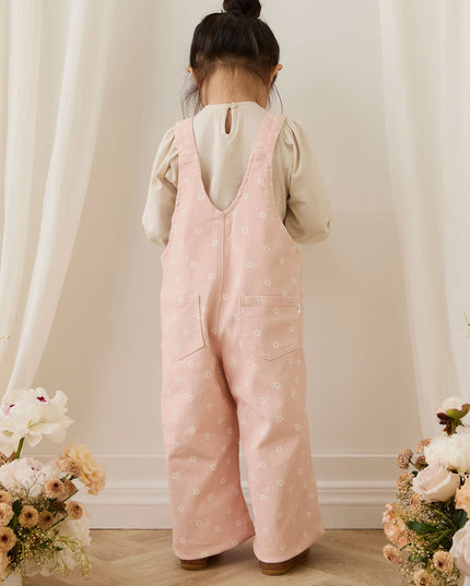 Girl wearing pink overalls with white flowers