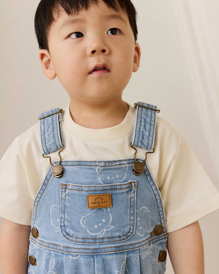 Child wearing blue denim overalls with bear pattern