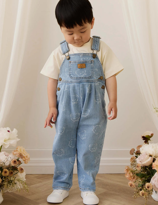 Child wearing blue denim overalls with bear pattern