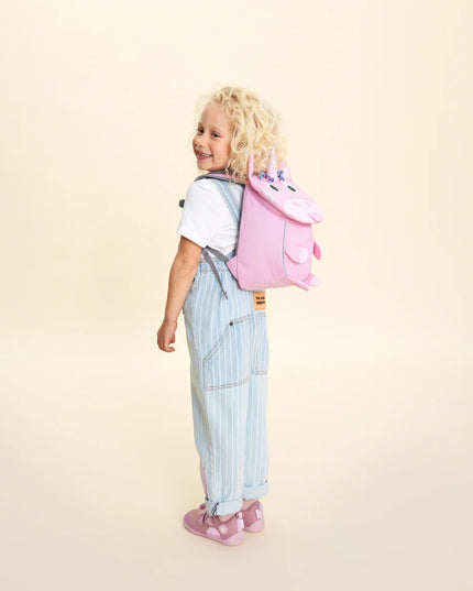 A child wearing a pink unicorn-shaped backpack 