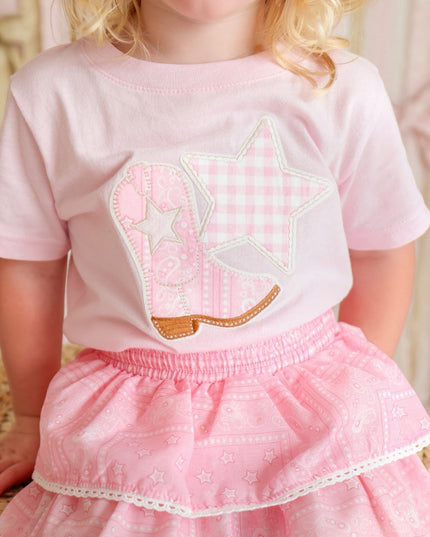 Girl wearing pink t-shirt with cowboy boot and star patch and bandana skirt