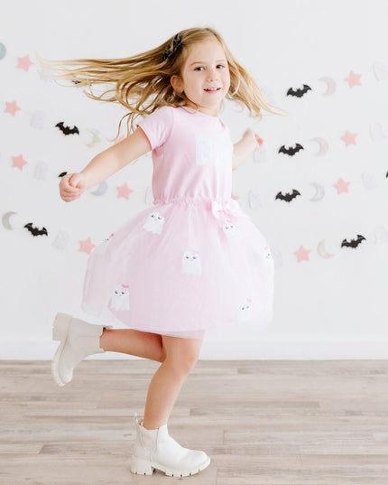 A girl twirling wearing a pink tutu dress with sequin 'Boo' and ghost details