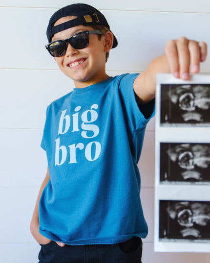 Boy holding sonogram wearing blue big bro t-shirt