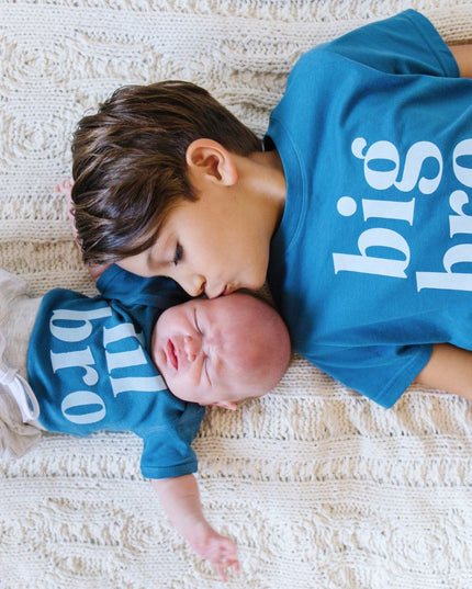 Two children wearing matching blue big bro/lil bro shirts