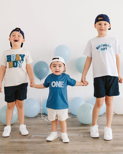 Three children wearing birthday outfits