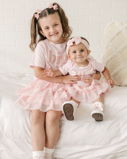 girls wearing matching "big sis" and "lil sis" outfits