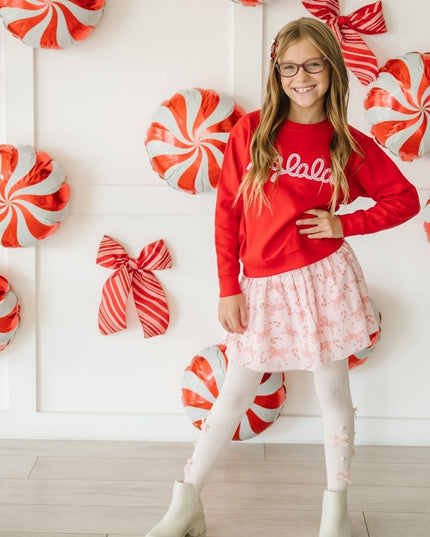 Girl wearing fa-la-la sweatshirt and pink tutu with candy cane and bow print 