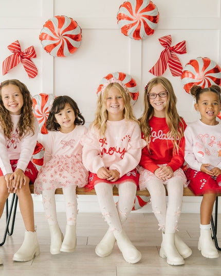 5 Girls sitting on a bench wearing festive Christmas outfits