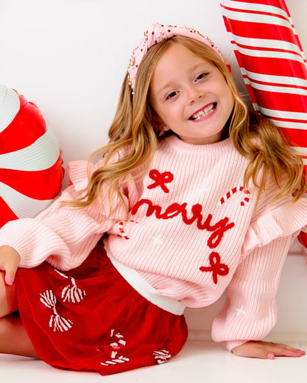 Girl wearing red tutu with red and white sequin candy canes and bows and pink merry sweater 