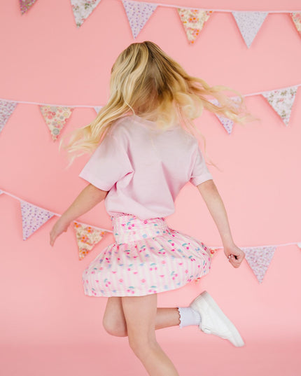 Girl wearing pink floral and cherry skort twirling