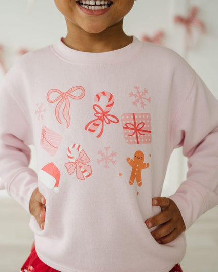 Girl wearing pink crewneck sweatshirt with fun Christmas graphics