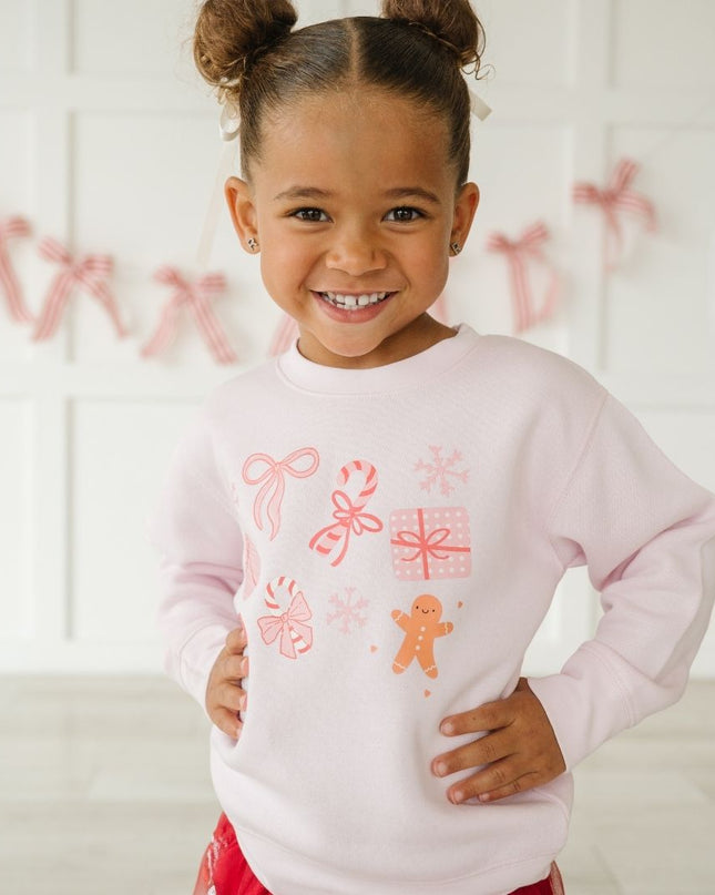 Girl wearing pink crewneck sweatshirt with fun Christmas graphics