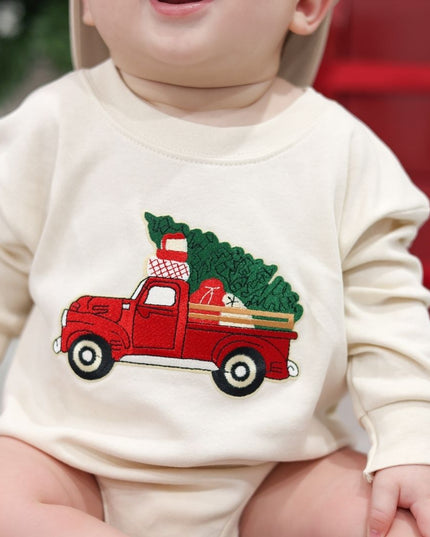 Baby wearing natural color long sleeve romper with a red tuck carrying a Christmas tree patch