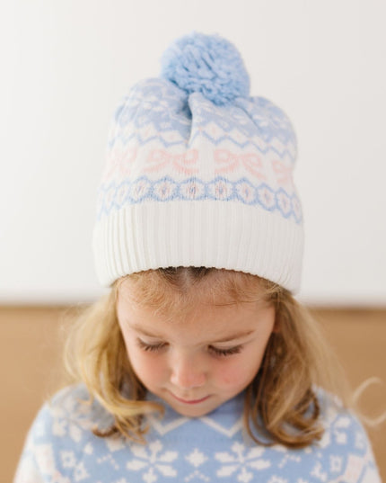Girl wearing blue and pink fair isle beanie with blue pom-pom on top