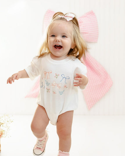 Baby wearing white shirt with floral and bow watercolor design 